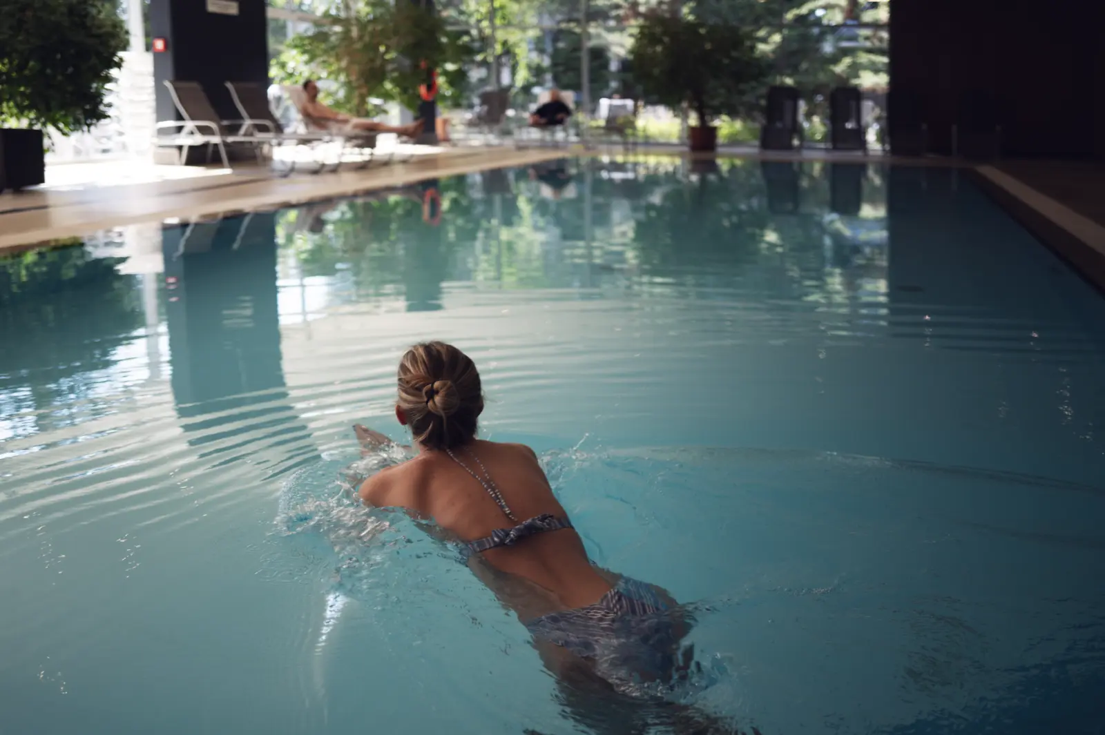 Junge Frau im Pool vom Manhattan Club Brunn, im Hintergrund Liegen und Garten